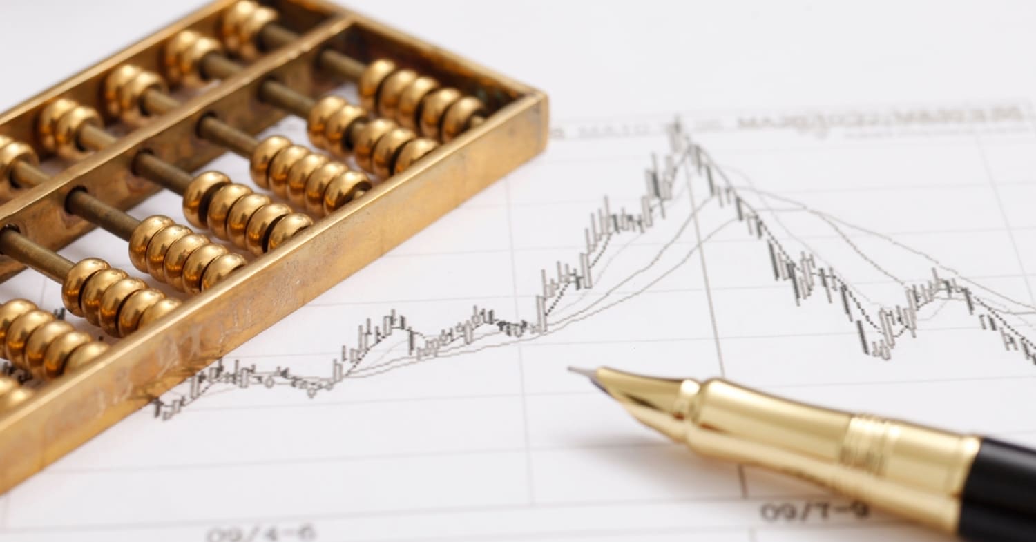 A gold abacus and pen rest on a financial chart with rising and falling line graphs, symbolizing advanced tax strategy in action.