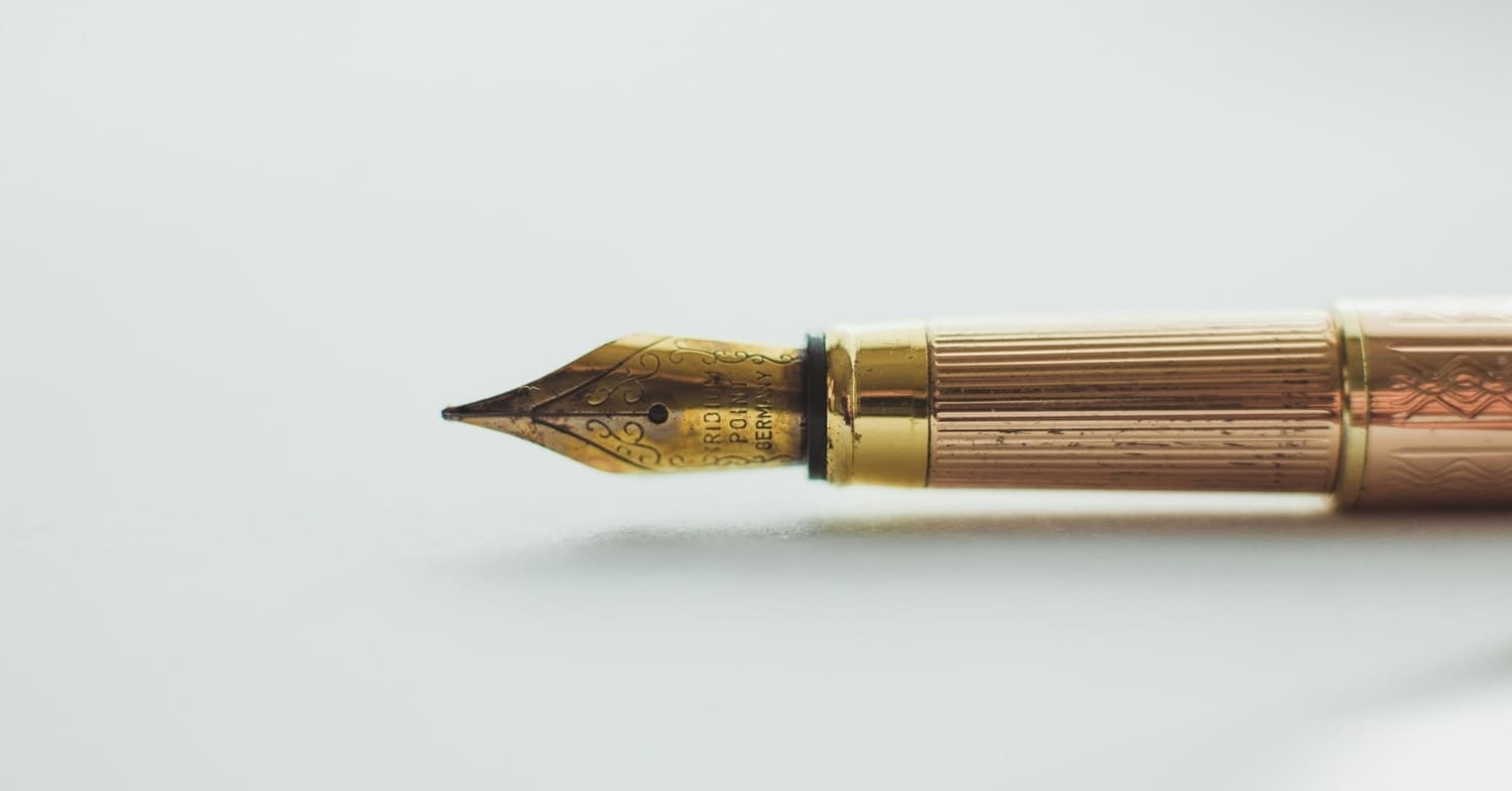 Close-up of a gold fountain pen nib with ornate engravings on a white background, ideal for the discerning tax strategist.