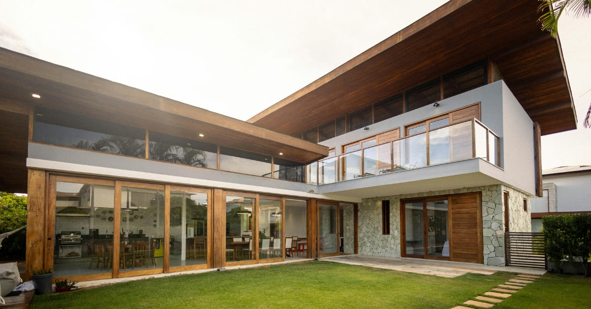 Modern house with large windows, stone accents, and a sloped roof overlooking a green lawn—ideal for a real estate investor CPA seeking smart tax planning for real estate investors.