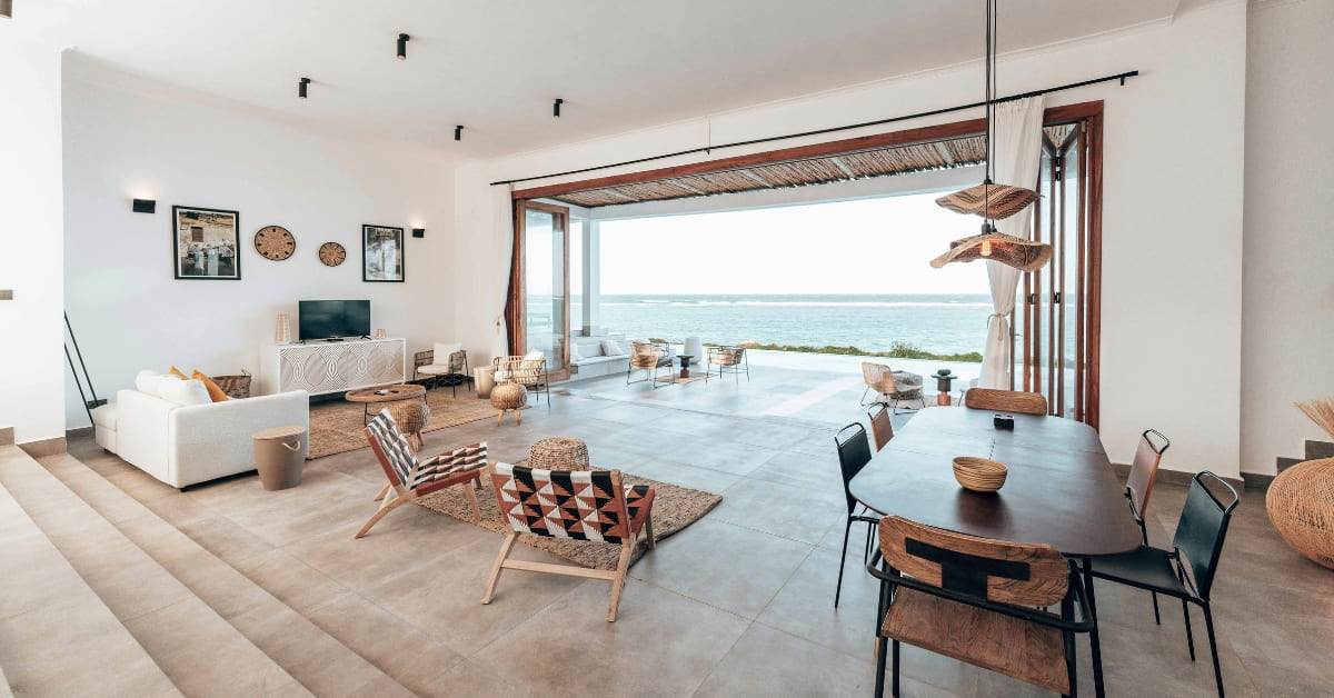 Spacious modern living and dining room with ocean view, open to a large patio and stylish decor—perfect for those considering short-term rental tax strategy to maximize returns on your real estate investment.